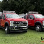 Two red Warrior Brush Trucks parked on a grassy field, designed for wildfire suppression with specialized equipment and durable construction.