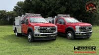 Two red Warrior Brush Trucks parked on a grassy field, designed for wildfire suppression with specialized equipment and durable construction.